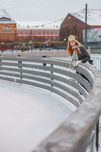 Rear view of woman standing on railing