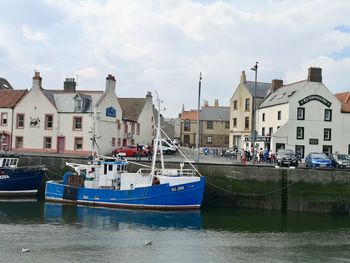 Sailboats moored on harbor by buildings in city