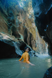 Full length of woman standing on rock in sea