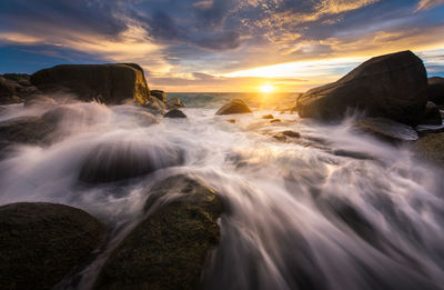 Scenic view of waterfall against sky during sunset