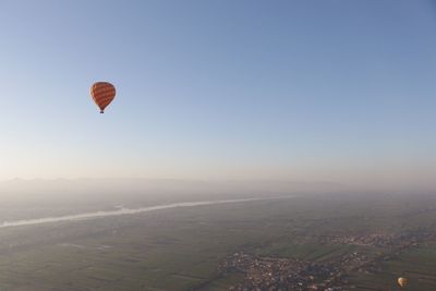 Hot air balloons flying over landscape against clear sky