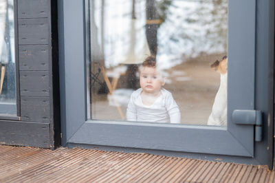 Portrait of young woman looking through window