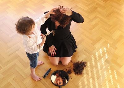 High angle view of child cutting hair of woman
