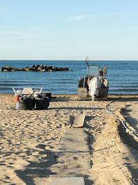 Deck chairs on beach against sky