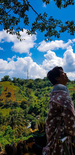 Rear view of man looking at trees against sky