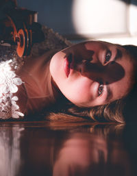 Portrait of young woman holding violin while lying down at home