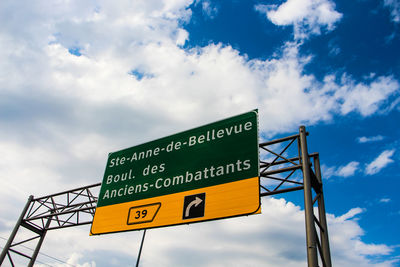 Low angle view of sign board against cloudy sky