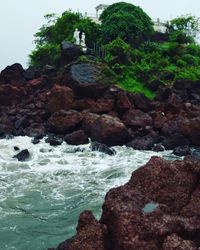 Scenic view of rocks by sea against sky