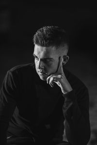 Portrait of young man against black background