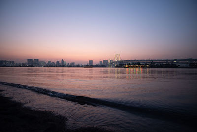 City by sea against clear sky at sunset