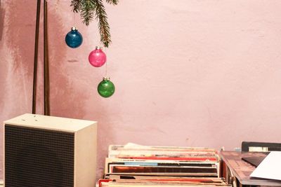 Christmas baubles hanging over documents at table against wall