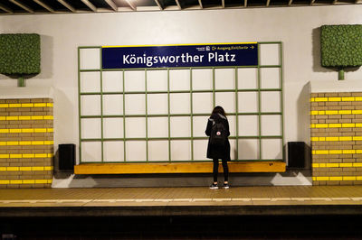 Rear view of woman standing at railroad station