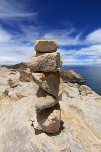 Stack of rocks by sea against sky