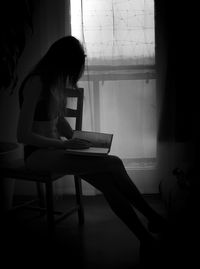 Side view of woman sitting on table at home