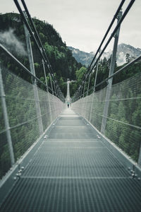 Footbridge amidst trees against sky