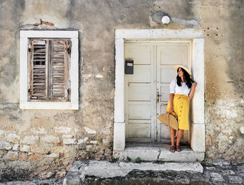 Portrait of an attractive young woman standing at an old door.
