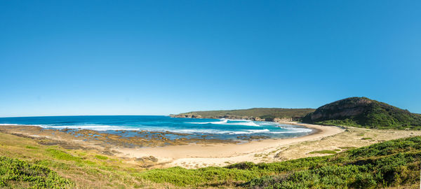 Scenic view of beach against clear blue sky