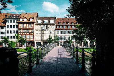 Footpath amidst buildings against sky