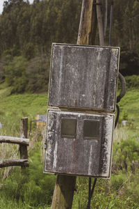 Close-up of birdhouse on wooden post in field