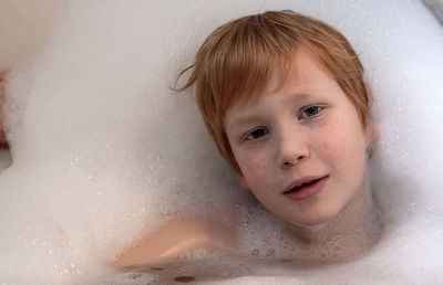 Portrait of boy taking bubble bath in bathroom