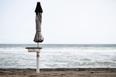 Wooden post on beach against clear sky