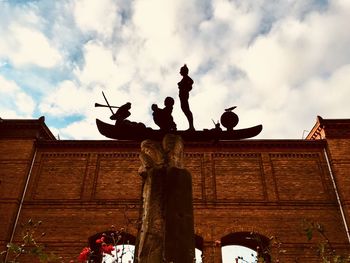 Low angle view of statues against cloudy sky