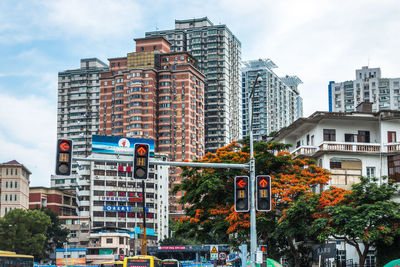 Buildings by stoplights against sky in city