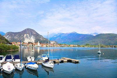 Boats moored at harbor against sky