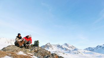 People on snow covered mountain against blue sky