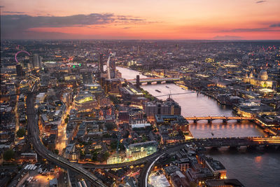 High angle view of illuminated buildings by river during sunset