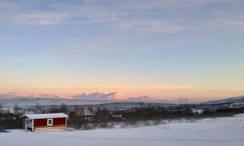 Scenic view of snowcapped field against sky during sunset