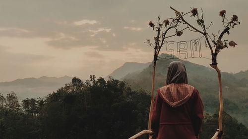 Rear view of woman looking at mountains against sky