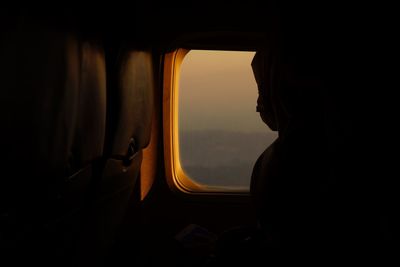 Silhouette man looking through airplane window