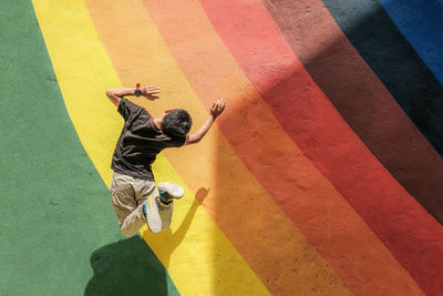 Rear view of boy jumping against colorful wall