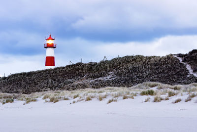 Lighthouse on street amidst buildings against sky