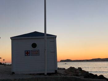 Built structure on beach against sky during sunset