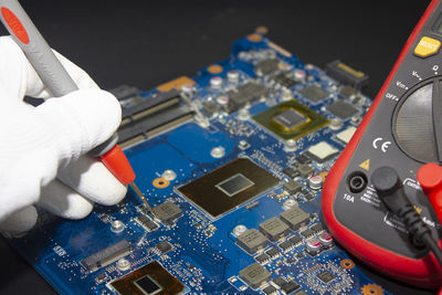 Computer repair service. engineer repairing laptop motherboard., measure electronic components.