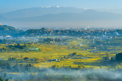 Scenic view of field by mountains against sky