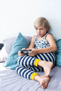 Boy holding joystick gaming controller in hands, playing video game at home.