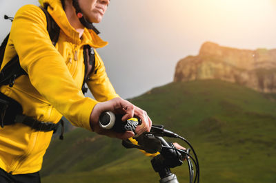 Close-up of a young woman cyclist holding the handlebars of her mountain bike against the backdrop 