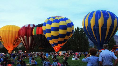 Group of people and hot air balloons against sky