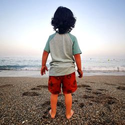 Rear view of woman standing at beach