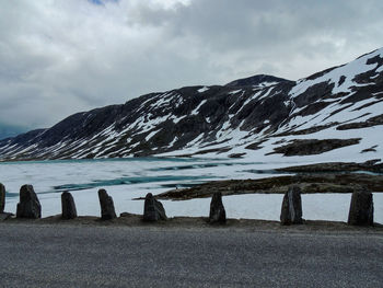 Scenic view of sea by snowcapped mountains against sky