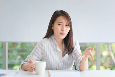 Portrait of young woman holding coffee cup