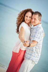 Mature couple dancing at beach against sky