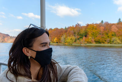 Woman wearing black face mask on a tourist boat at plitvice lakes national park in croatia