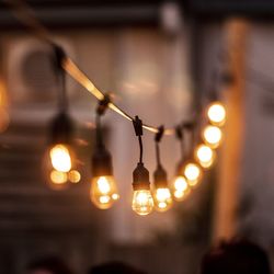 Close-up of illuminated light bulbs hanging at restaurant