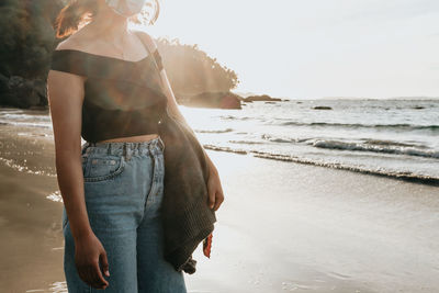 Rear view of woman standing at beach