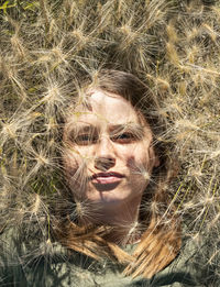 Portrait of  young woman lying among fluffy spikelets of barley, relaxation and enjoying on nature