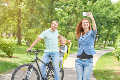 Happy friends with bicycle against trees